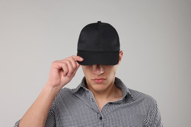 Photo of Young man wearing stylish black baseball hat on light grey background