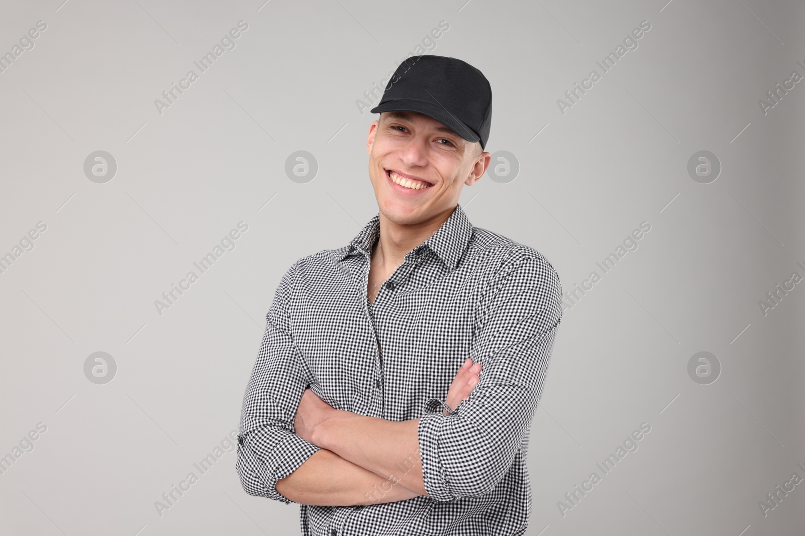Young man wearing stylish black baseball hat on light grey background Photo of Young man wearing stylish black baseball hat on light grey background
