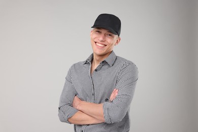Photo of Young man wearing stylish black baseball hat on light grey background