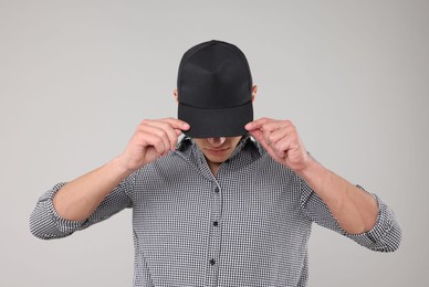 Photo of Young man wearing stylish black baseball hat on light grey background