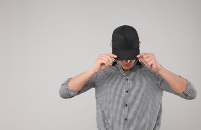Photo of Young man wearing stylish black baseball hat on light grey background, space for text
