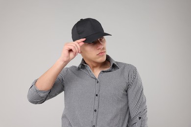 Photo of Young man wearing stylish black baseball hat on light grey background