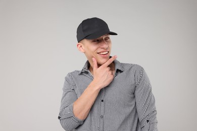 Photo of Young man wearing stylish black baseball hat on light grey background