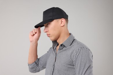 Photo of Young man wearing stylish black baseball hat on light grey background