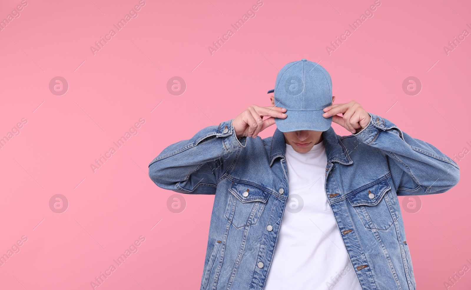 Young man wearing stylish denim baseball hat on pink background, space for text Photo of Young man wearing stylish denim baseball hat on pink background, space for text
