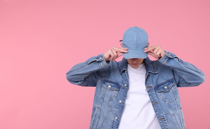 Photo of Young man wearing stylish denim baseball hat on pink background, space for text