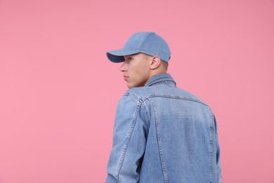 Photo of Young man wearing stylish denim baseball hat on pink background, space for text