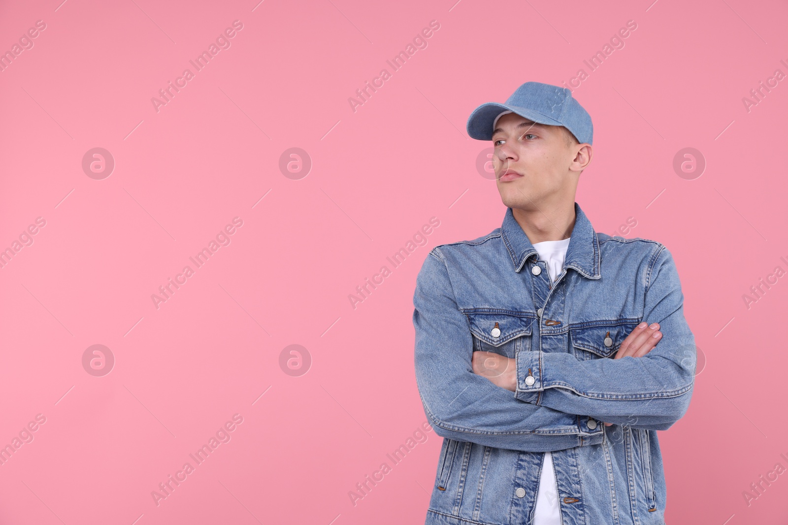 Young man wearing stylish denim baseball hat on pink background, space for text Photo of Young man wearing stylish denim baseball hat on pink background, space for text