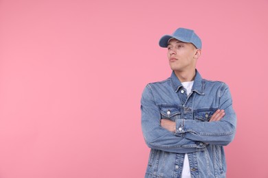 Photo of Young man wearing stylish denim baseball hat on pink background, space for text