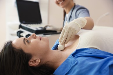 Photo of Sonographer conducting ultrasound examination of woman's thyroid gland in clinic, closeup