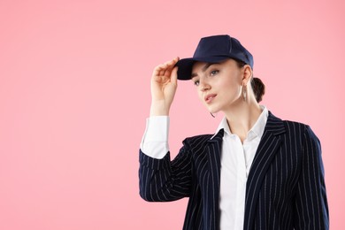 Photo of Beautiful woman in stylish baseball hat on pink background. Space for text
