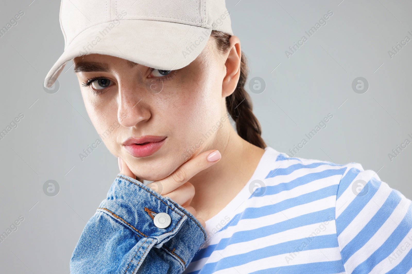 Portrait of beautiful woman in stylish baseball hat on grey background, closeup Photo of Portrait of beautiful woman in stylish baseball hat on grey background, closeup