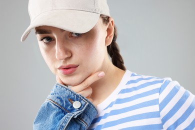 Photo of Portrait of beautiful woman in stylish baseball hat on grey background, closeup