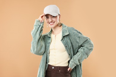 Photo of Portrait of smiling woman in stylish baseball hat on beige background