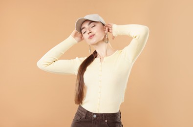 Photo of Beautiful woman in stylish baseball hat posing on beige background