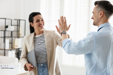 Photo of Marketing. Colleagues giving high five in office