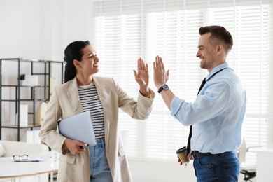 Photo of Marketing. Colleagues giving high five in office