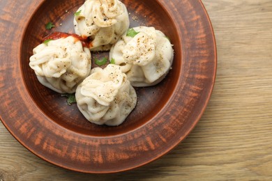 Photo of Tasty khinkali with spices on wooden table, top view