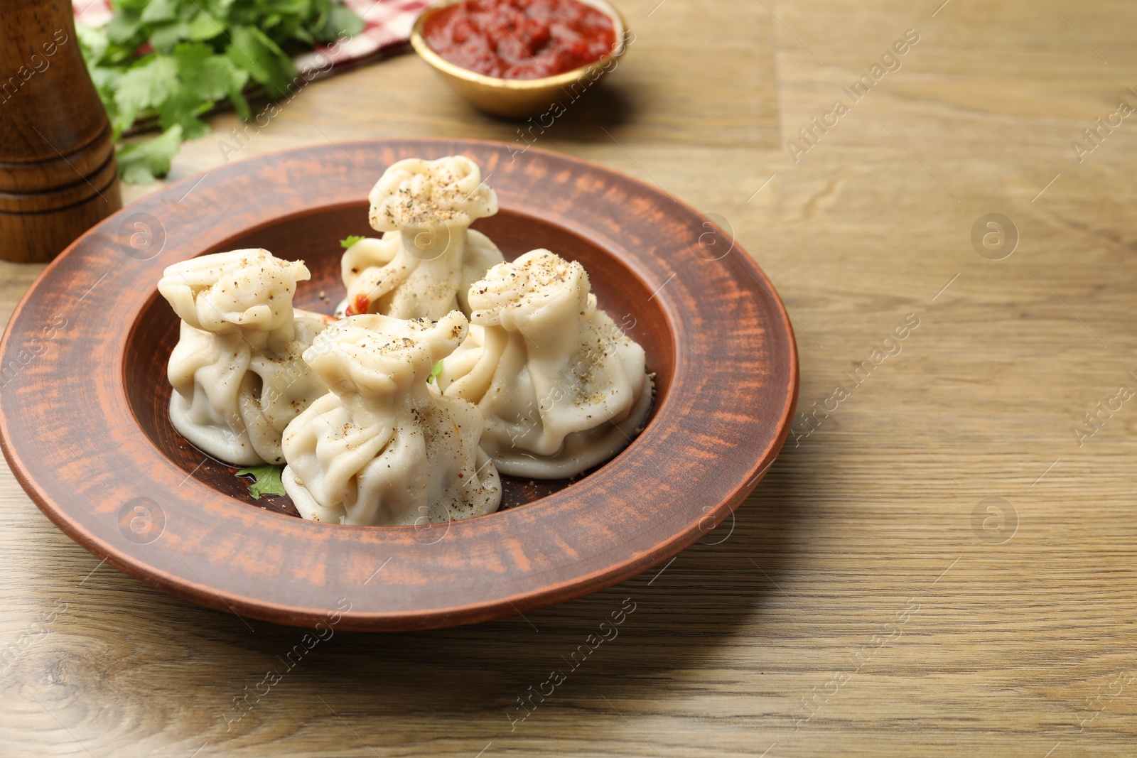 Tasty khinkali with sauce and spices on wooden table Photo of Tasty khinkali with sauce and spices on wooden table
