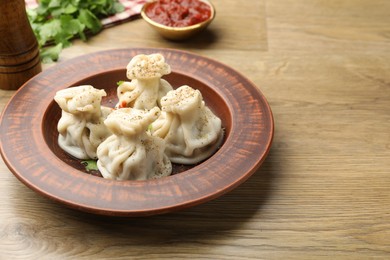Photo of Tasty khinkali with sauce and spices on wooden table