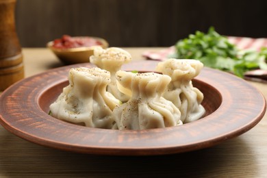 Photo of Tasty khinkali with spices on wooden table, closeup