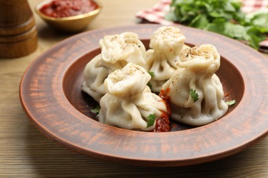 Photo of Tasty khinkali with spices on wooden table, closeup