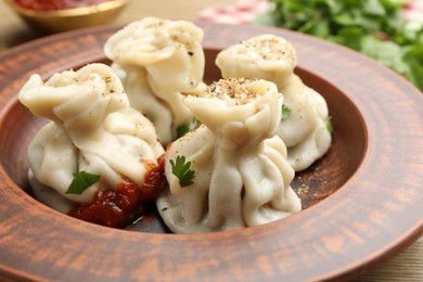 Photo of Tasty khinkali with spices on wooden table, closeup