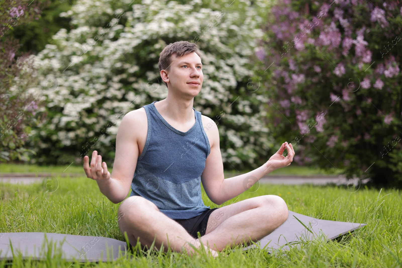 Young man practicing yoga on mat in park Photo of Young man practicing yoga on mat in park