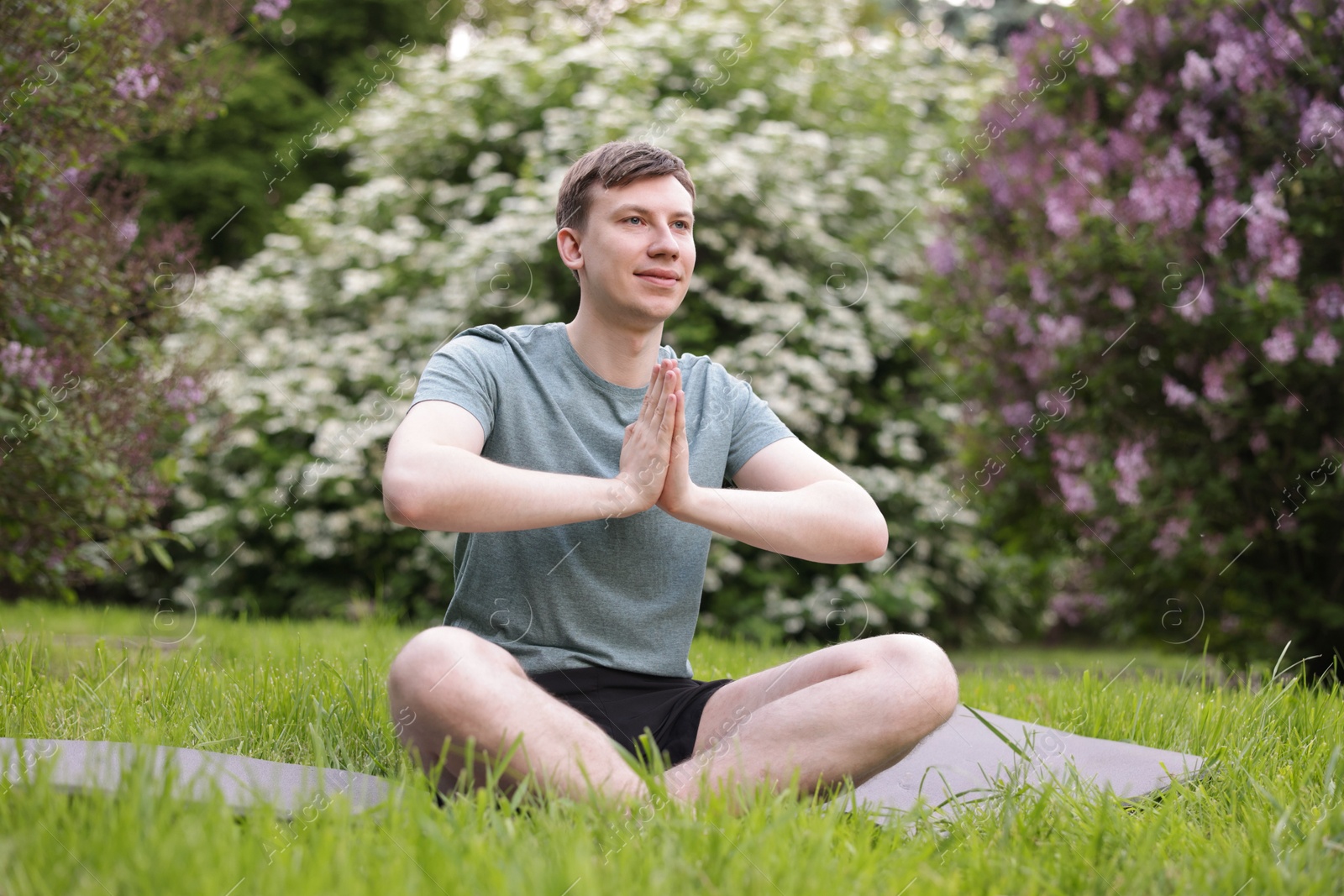 Young man practicing yoga on mat in park Photo of Young man practicing yoga on mat in park