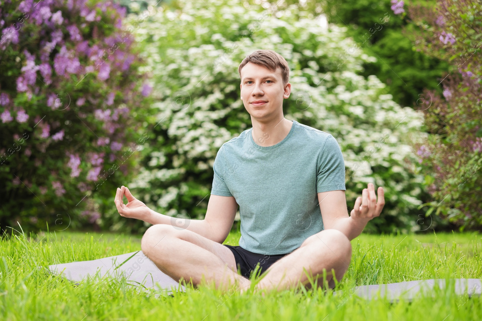 Young man practicing yoga on mat in park Photo of Young man practicing yoga on mat in park