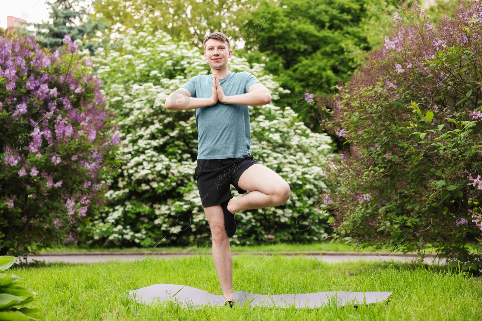 Young man practicing yoga on mat in park Photo of Young man practicing yoga on mat in park