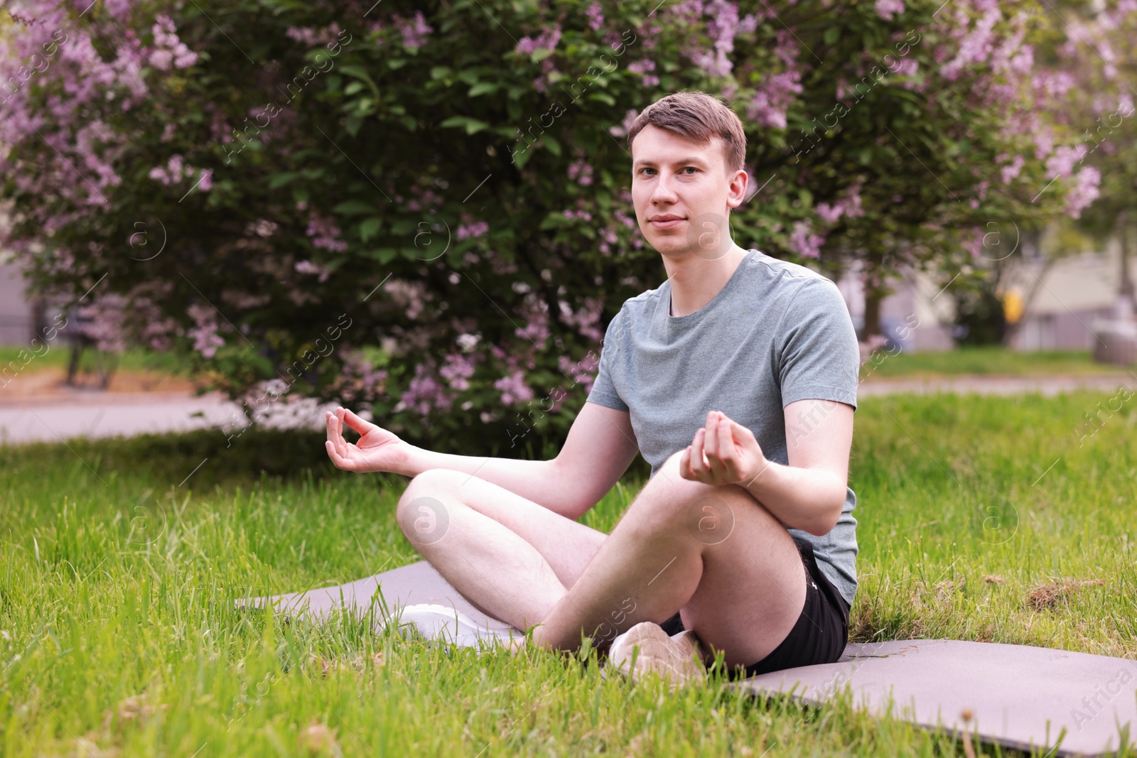 Young man practicing yoga on mat in park Photo of Young man practicing yoga on mat in park