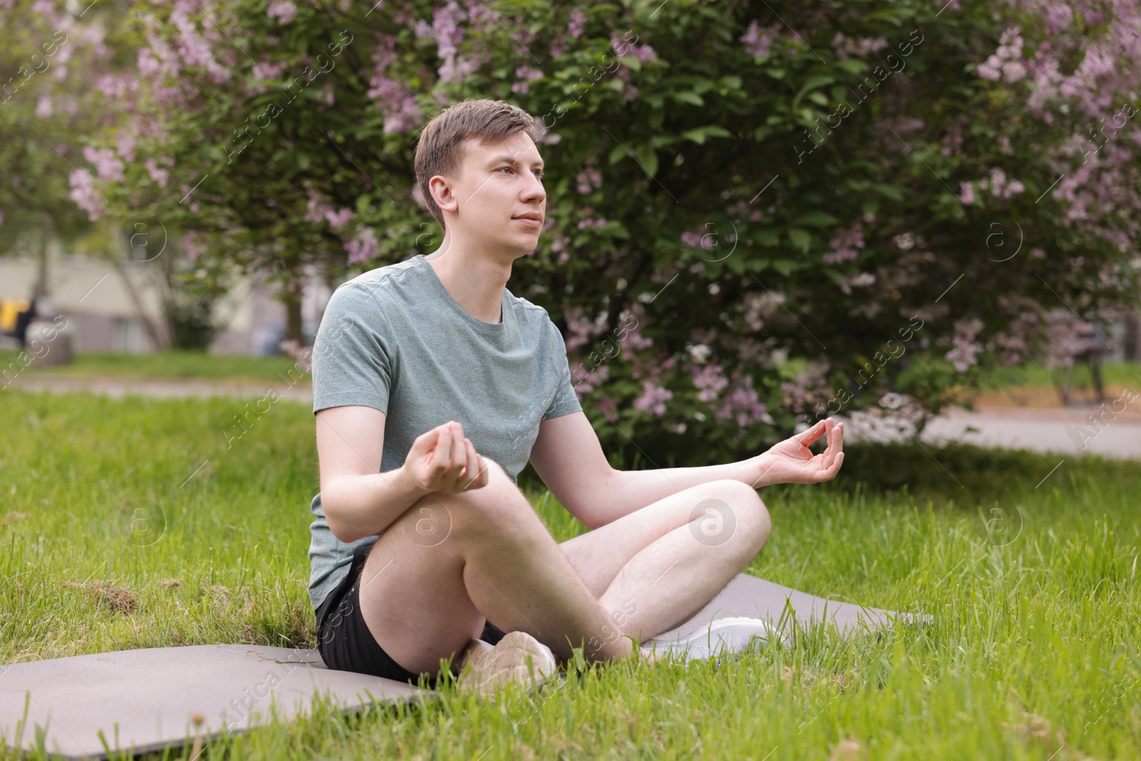 Young man practicing yoga on mat in park Photo of Young man practicing yoga on mat in park