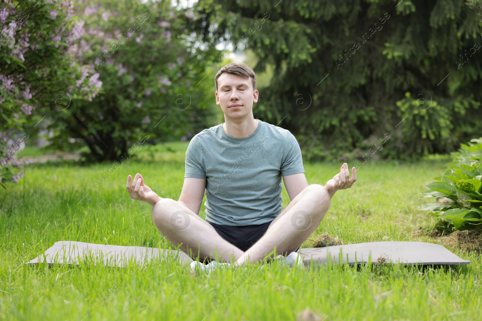 Young man practicing yoga on mat in park Photo of Young man practicing yoga on mat in park