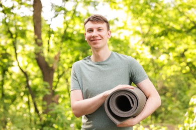 Photo of Young man with yoga mat in park