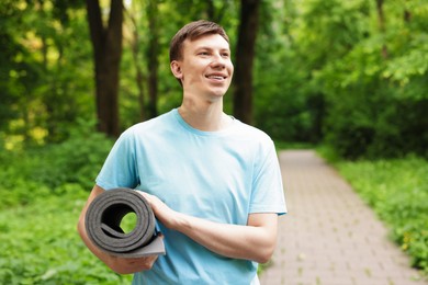 Photo of Young man with yoga mat in park