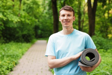 Photo of Young man with yoga mat in park