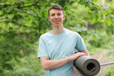 Photo of Young man with yoga mat in park