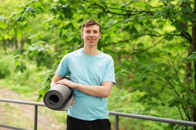 Photo of Young man with yoga mat in park