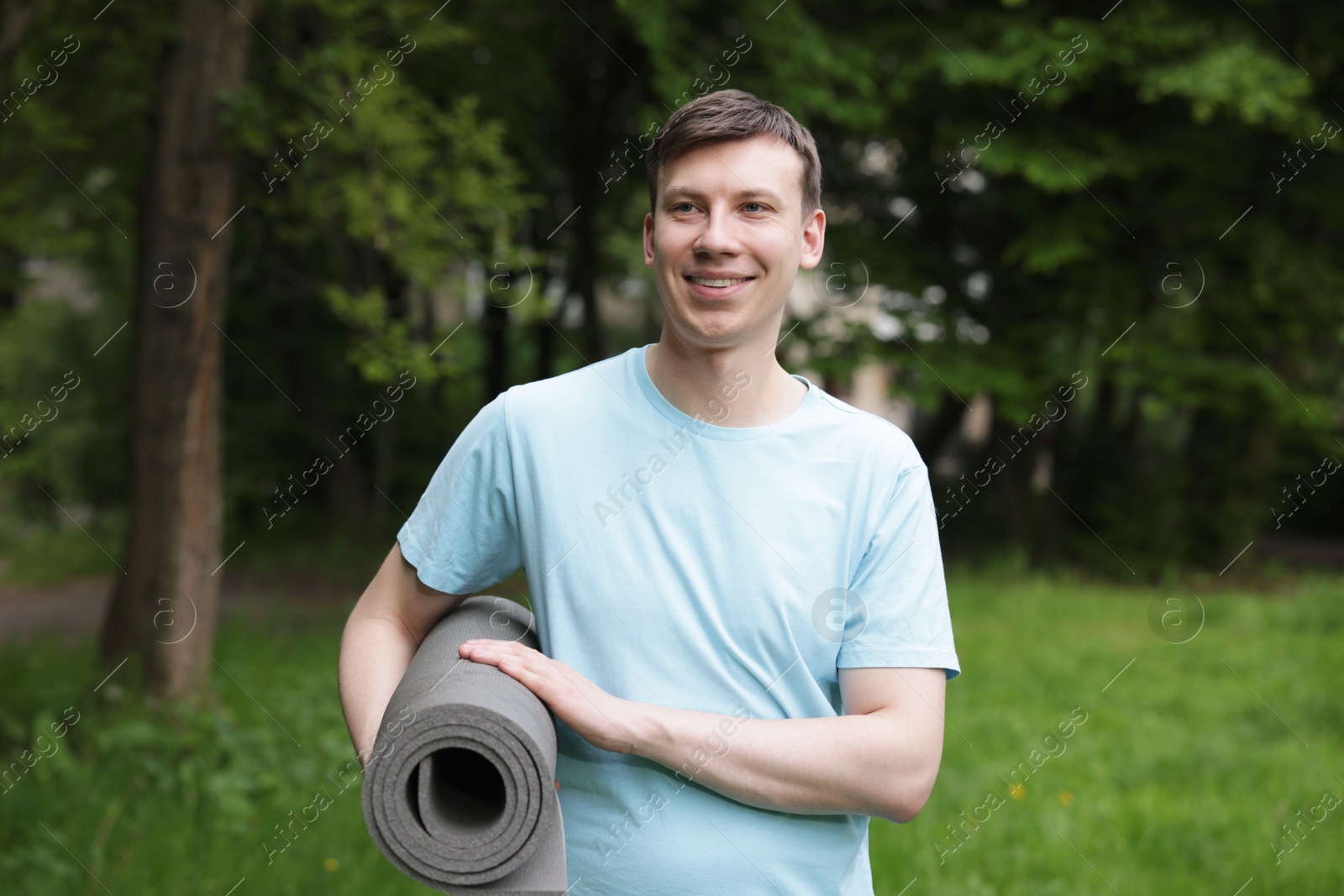 Young man with yoga mat in park Photo of Young man with yoga mat in park