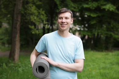 Photo of Young man with yoga mat in park