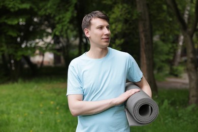 Photo of Young man with yoga mat in park