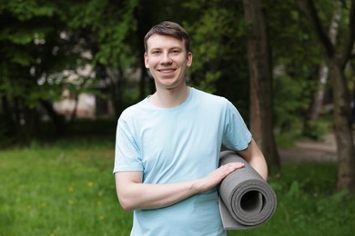 Photo of Young man with yoga mat in park