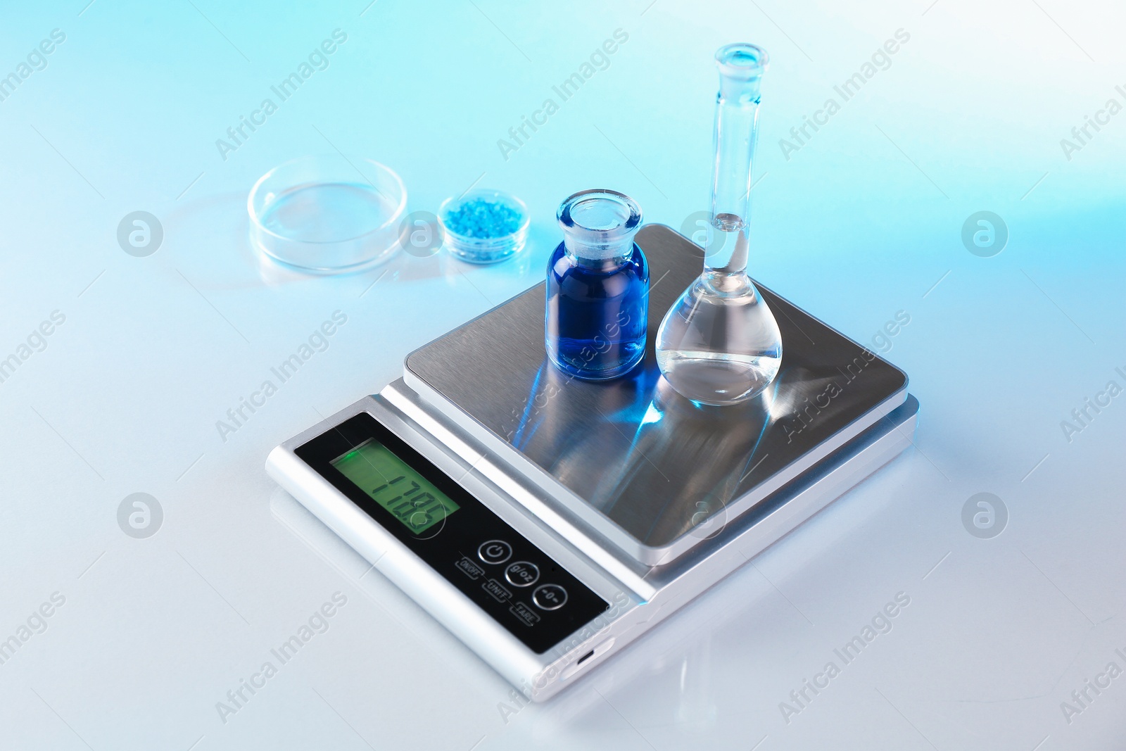 Scale with samples and laboratory glassware on white table in color lights, closeup Photo of Scale with samples and laboratory glassware on white table in color lights, closeup
