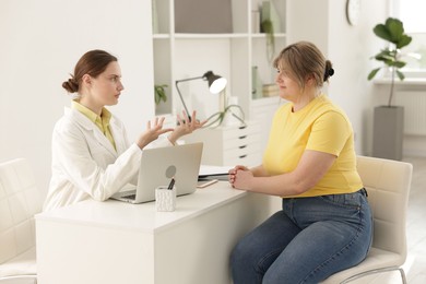 Photo of Weight loss. Nutritionist consulting overweight woman at white desk in clinic