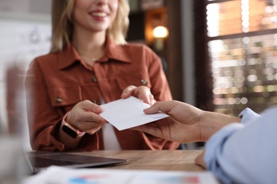 Photo of Money bonus. Employee receiving envelope from boss in office, closeup