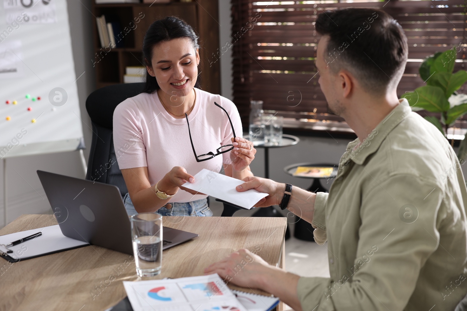 Money bonus. Boss giving envelope to employee in office Photo of Money bonus. Boss giving envelope to employee in office