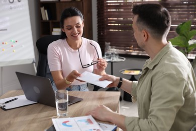 Photo of Money bonus. Boss giving envelope to employee in office