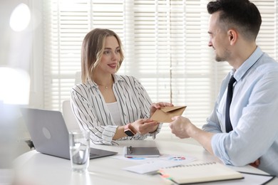 Photo of Money bonus. Boss giving envelope to employee in office