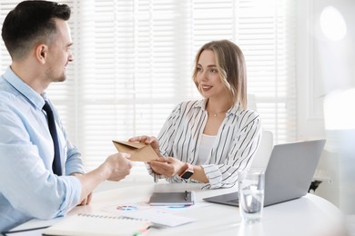 Photo of Money bonus. Boss giving envelope to employee in office